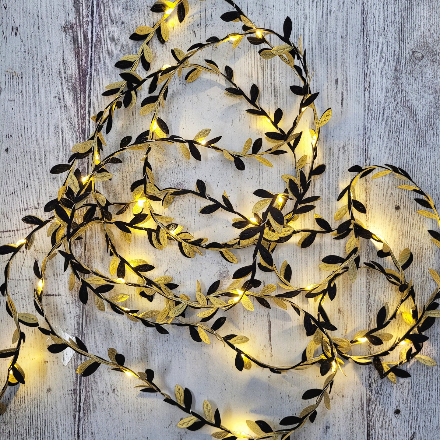 Delicate black and gold fairy lights on a grey wooden background