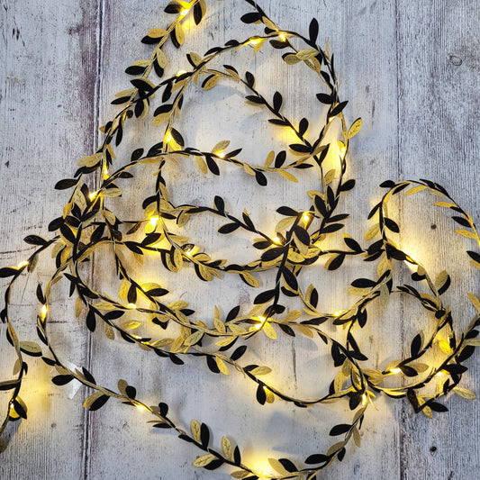 Delicate black and gold fairy lights on a grey wooden background